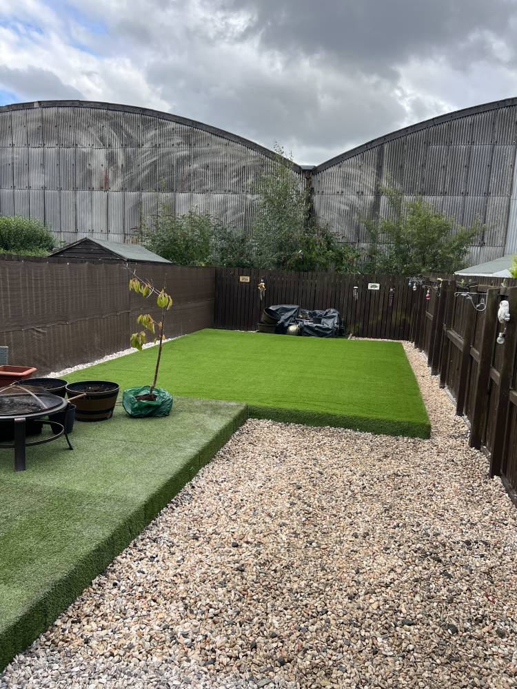 Artificial grass garden with gravel path and timber fencing
