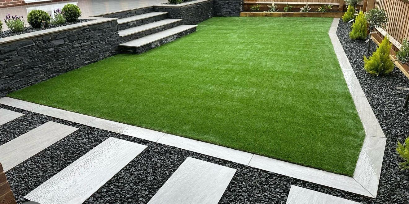Modern artificial grass garden with stone retaining wall and stepping stones