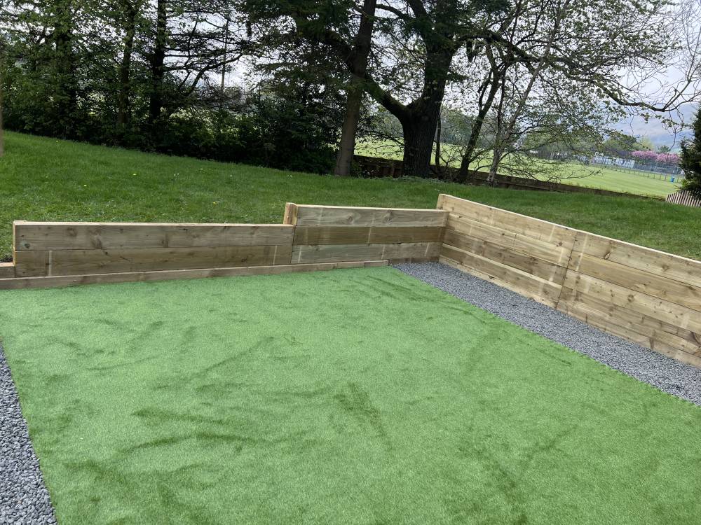 Artificial turf area with timber sleeper retaining walls and gravel surround