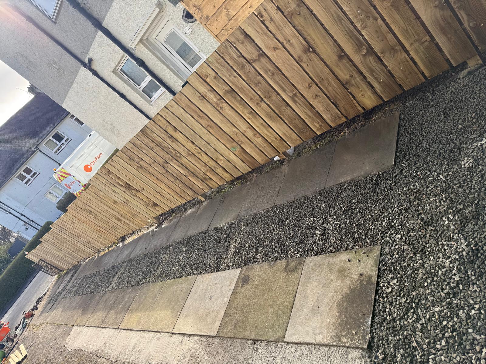 Completed close-board fence with gravel and paving slabs