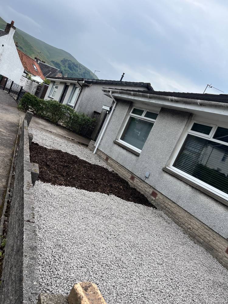 Gravel driveway with bark mulch planting beds in front garden
