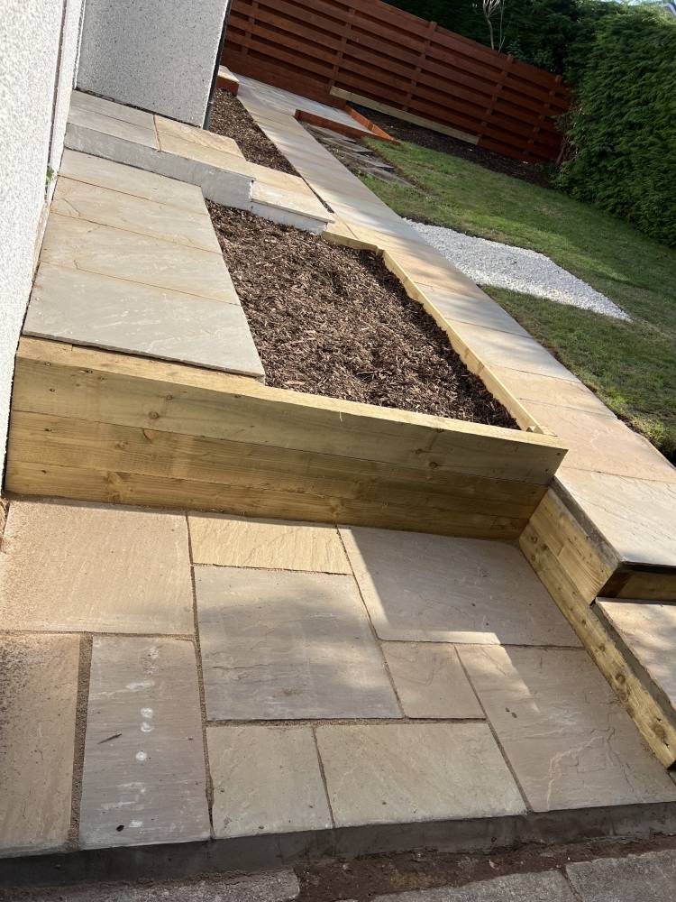 Close-up of Indian sandstone path and timber sleeper planters