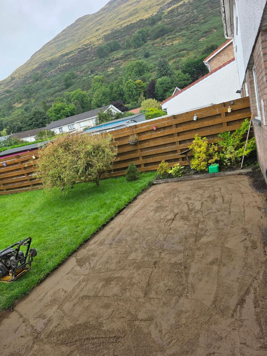 Compacted sub-base prepared for a sandstone patio beside the house