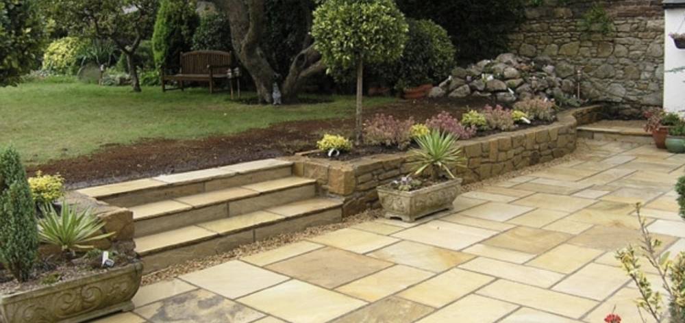 Sandstone patio with steps and stone wall