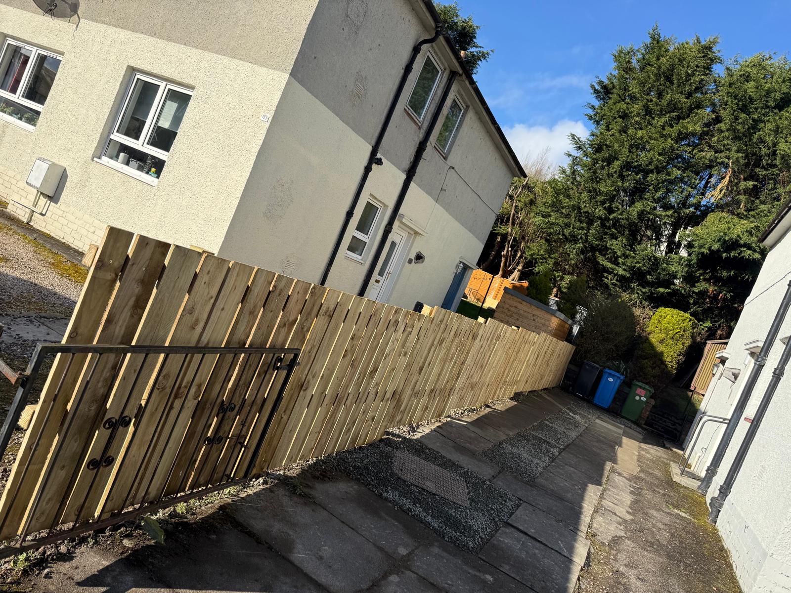 Finished close-board fence and gate on side path with blue sky