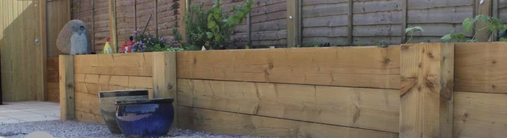 Timber sleeper raised planter with gravel garden path and ornaments