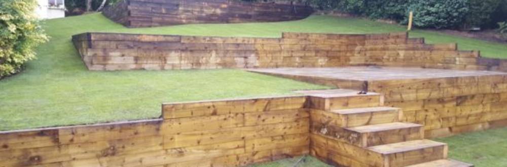 Tiered sleeper retaining wall with turf and steps