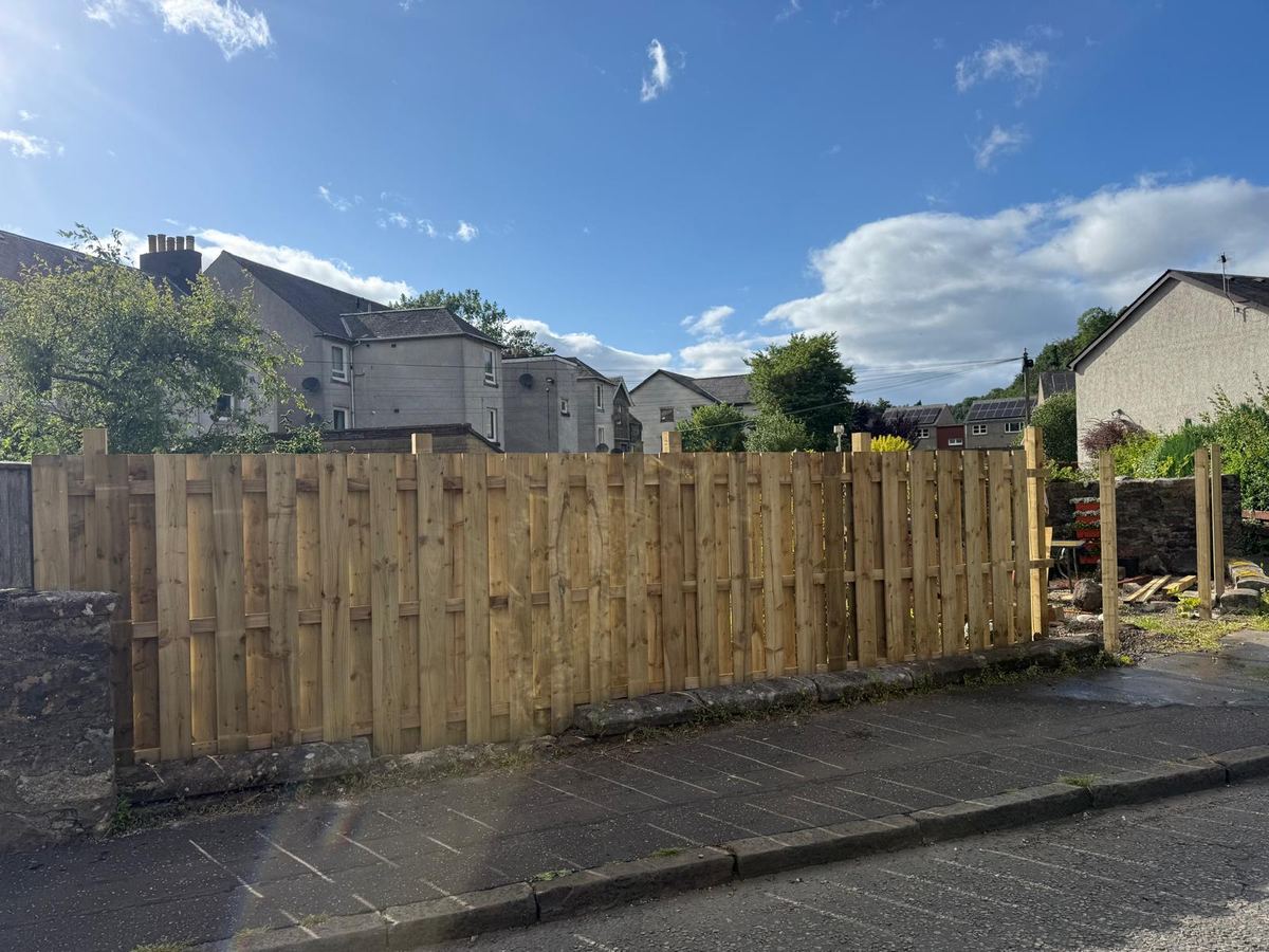 Completed timber boundary fence on a stone wall